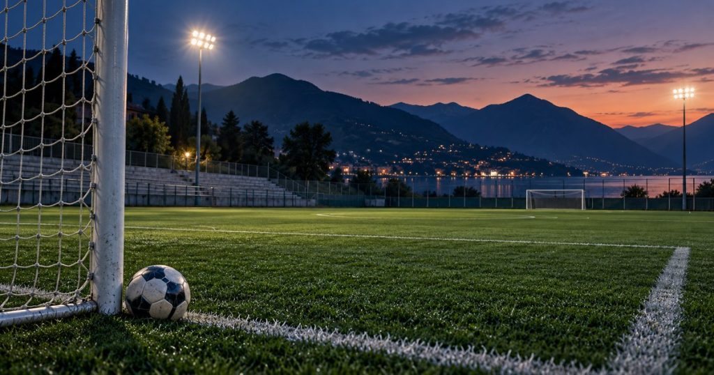 Campo da calcio vuoto al tramonto, con pallone e porta in primo piano. Immagine illustrativa generata con AI.